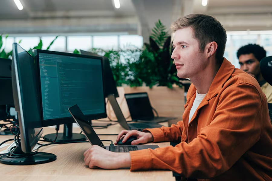 Мужчина в оранжевой рубашке смотрит код
