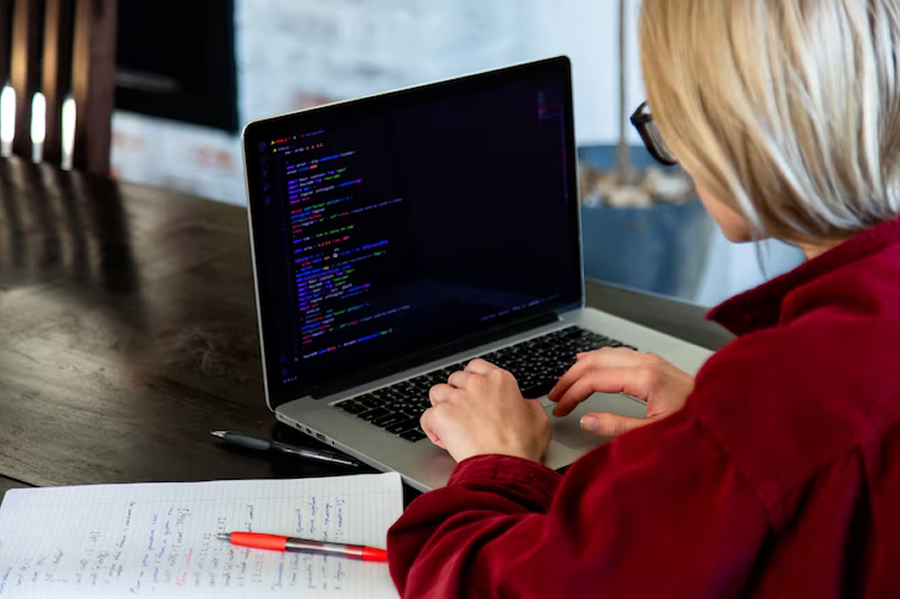 Девушка в красной рубашке пишет код на Питон