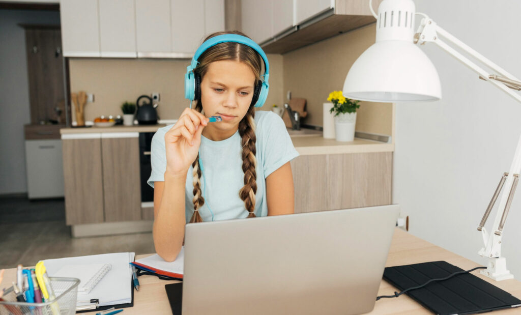 Девочка в наушниках смотрит в ноутбук