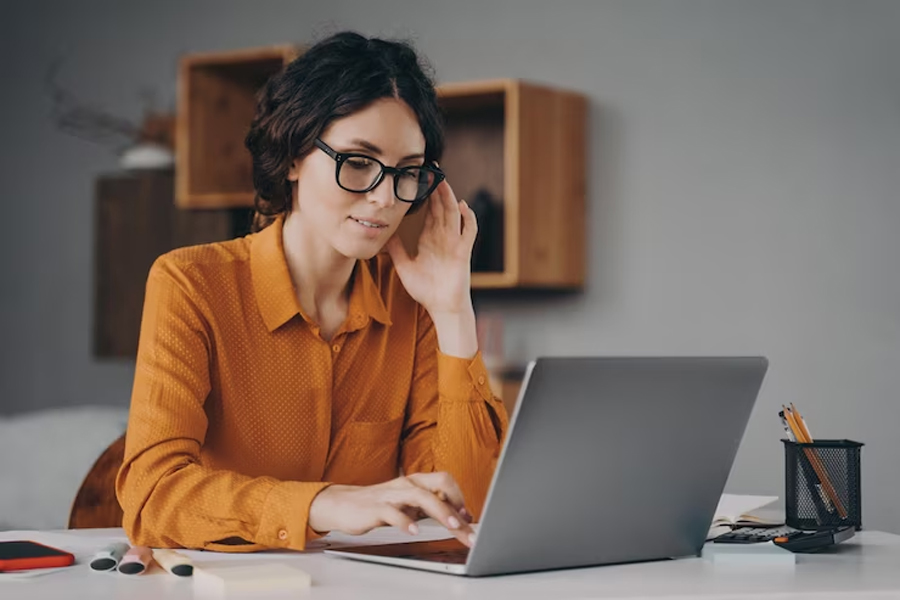 Девушка в очках печатает на компьютере