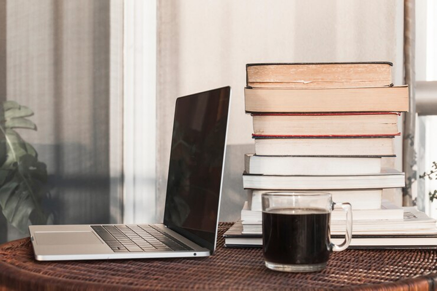Стол с ноутбуком, стопкой книг и кружкой кофе
