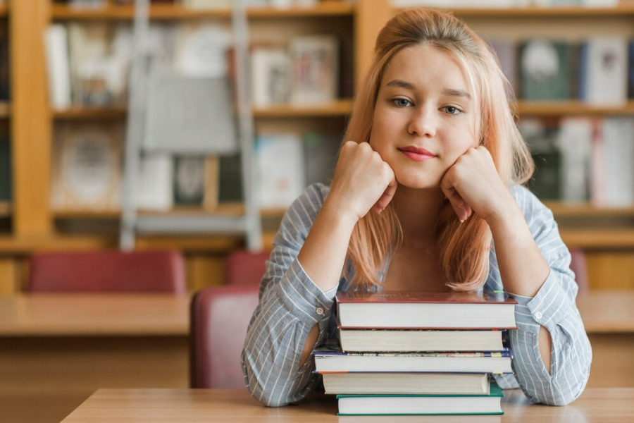 Девочка сидит за столом с книгами 